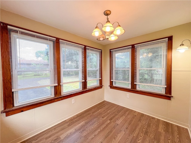 spare room with an inviting chandelier and hardwood / wood-style flooring