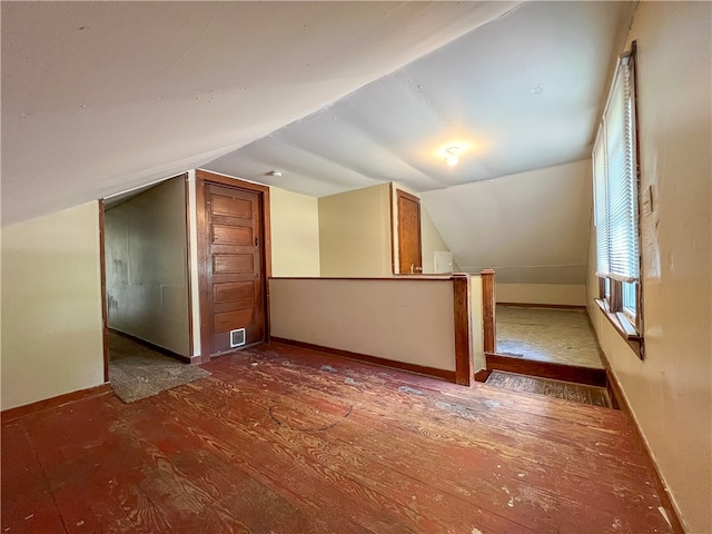 additional living space featuring dark wood-type flooring and vaulted ceiling