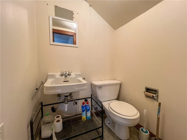 bathroom featuring sink, toilet, and lofted ceiling