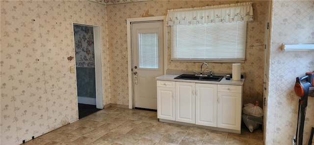 kitchen featuring sink, white cabinetry, and light tile floors