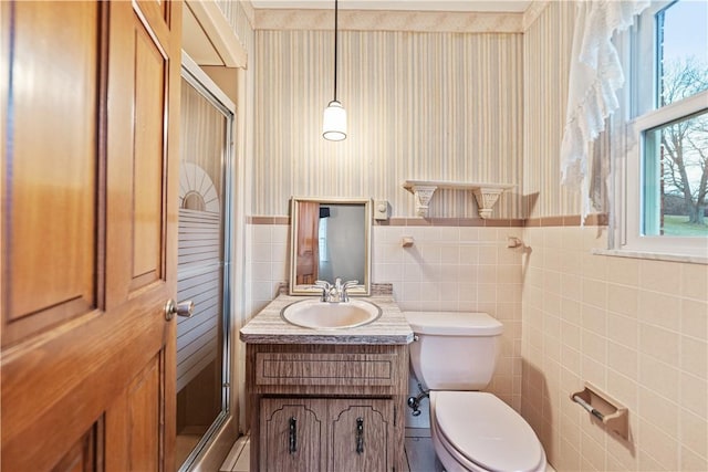 bathroom with walk in shower, vanity, tile walls, and toilet