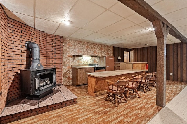 bar featuring a paneled ceiling, dishwasher, and a wood stove