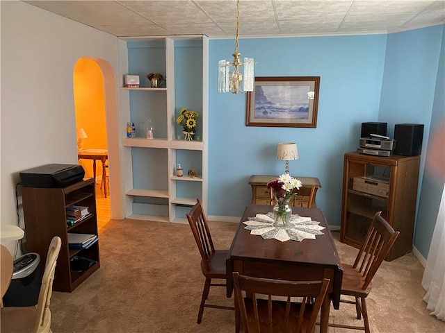 dining space featuring a chandelier, built in shelves, and carpet floors