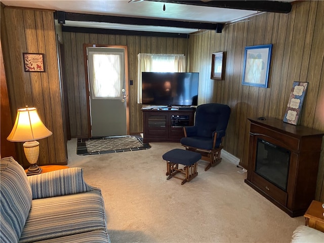 carpeted living room featuring wooden walls and beam ceiling