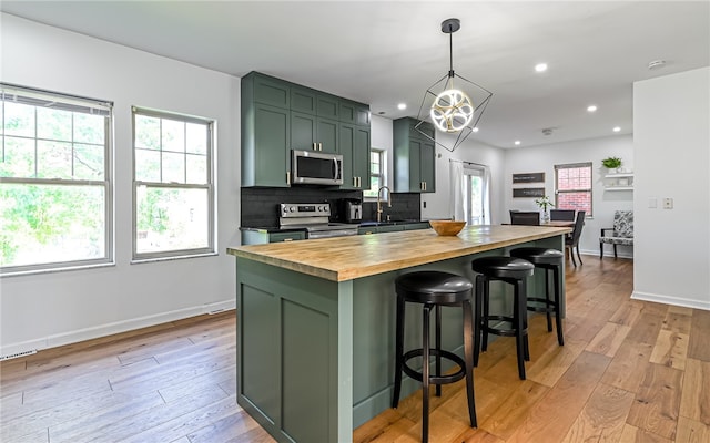 kitchen with decorative backsplash, light wood-type flooring, wooden counters, a center island, and stainless steel appliances