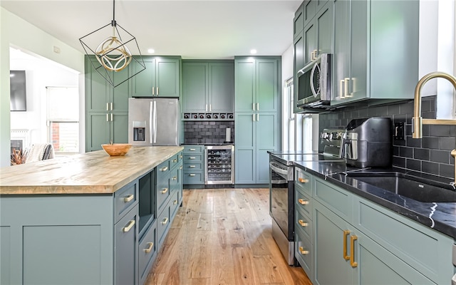 kitchen with light wood-type flooring, wooden counters, backsplash, pendant lighting, and appliances with stainless steel finishes