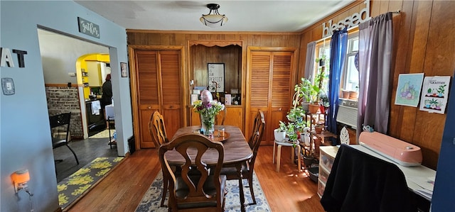 dining area featuring dark hardwood / wood-style floors, a fireplace, and wood walls