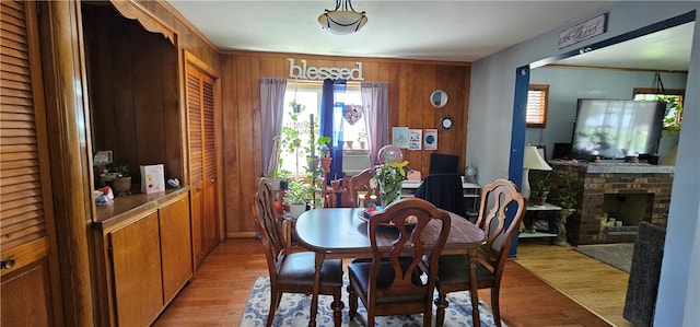 dining area featuring light hardwood / wood-style floors, a fireplace, and wooden walls