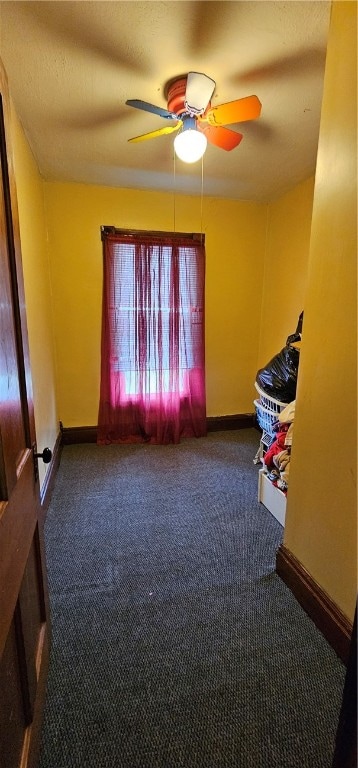 interior space featuring ceiling fan and dark carpet