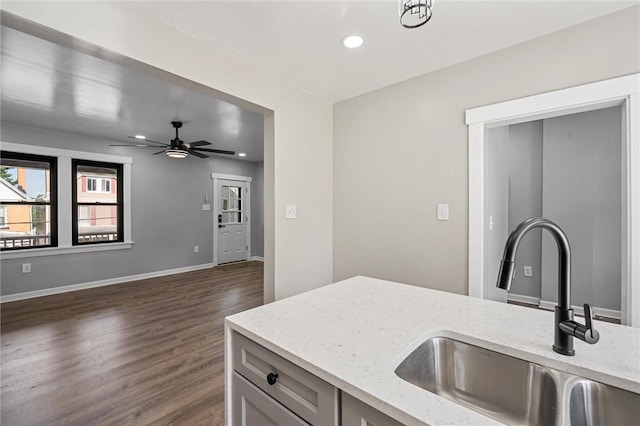 kitchen featuring ceiling fan, dark hardwood / wood-style flooring, light stone countertops, and sink