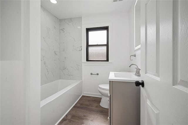 full bathroom featuring vanity, tiled shower / bath combo, wood-type flooring, and toilet