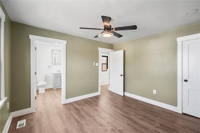 unfurnished bedroom with ensuite bathroom, ceiling fan, and light wood-type flooring