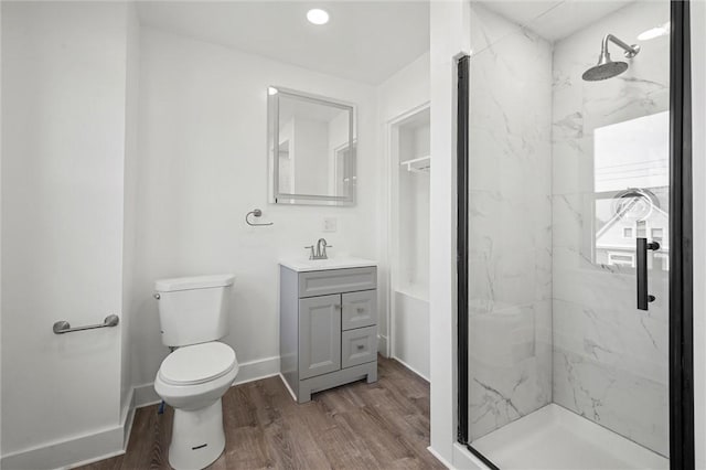 bathroom with vanity, a tile shower, toilet, and hardwood / wood-style flooring