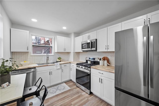 kitchen with backsplash, sink, white cabinets, and appliances with stainless steel finishes