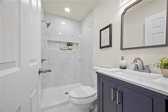 bathroom with vanity, toilet, and tiled shower