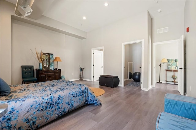 bedroom featuring a towering ceiling and hardwood / wood-style floors