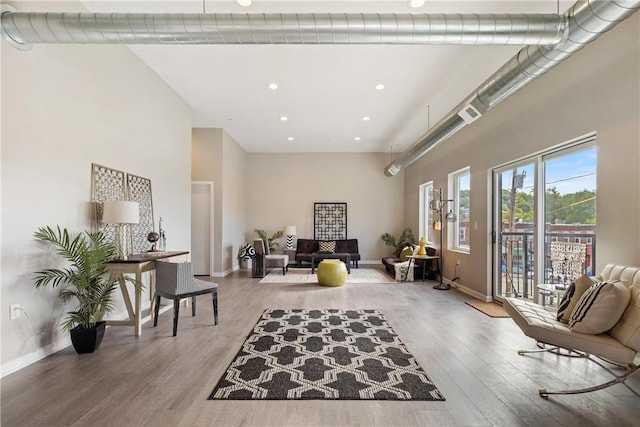 living area with a towering ceiling and wood-type flooring