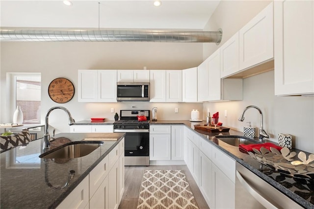 kitchen featuring stainless steel appliances, sink, white cabinets, and dark stone counters