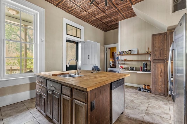 kitchen featuring wood counters, a wealth of natural light, stainless steel appliances, sink, and a center island with sink