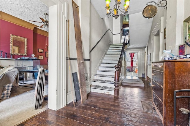 stairway featuring hardwood / wood-style floors and ceiling fan with notable chandelier