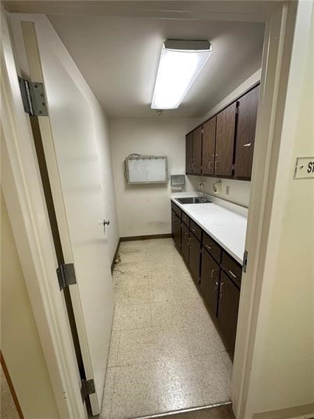 kitchen featuring dark brown cabinetry, sink, and light tile floors