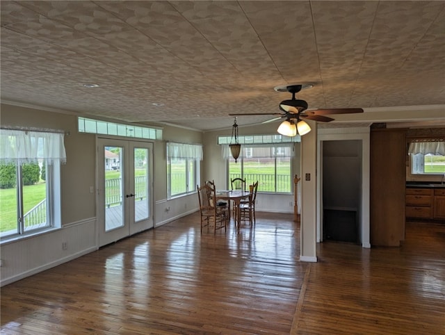 unfurnished dining area featuring ceiling fan, dark hardwood / wood-style flooring, crown molding, and french doors