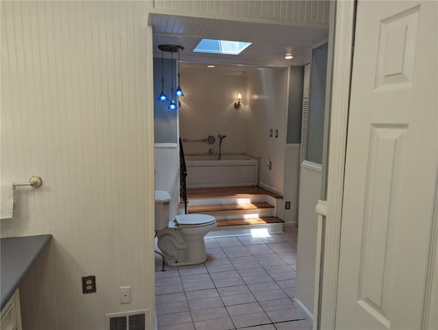 bathroom with tile flooring, toilet, and a skylight