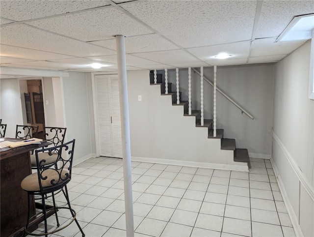 basement featuring light tile floors and a drop ceiling