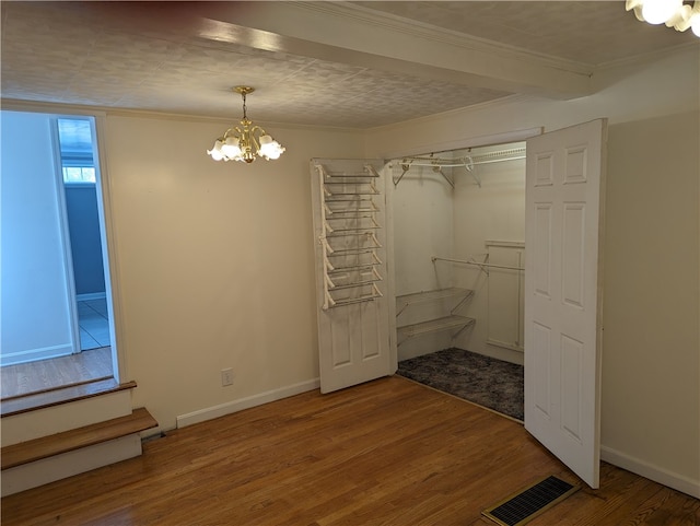 unfurnished bedroom with wood-type flooring, a closet, and a chandelier