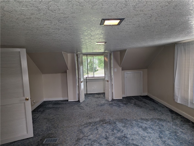 bonus room featuring a textured ceiling, lofted ceiling, and dark carpet