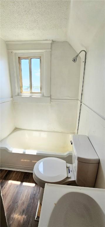 bathroom featuring bathing tub / shower combination, lofted ceiling, hardwood / wood-style floors, and a textured ceiling