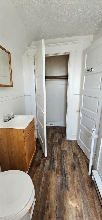 bathroom with vanity, a textured ceiling, hardwood / wood-style flooring, and toilet