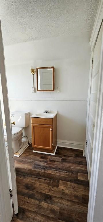 bathroom with hardwood / wood-style flooring, vanity, toilet, and a textured ceiling