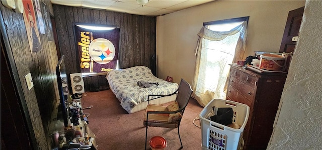 carpeted bedroom featuring a drop ceiling and wooden walls