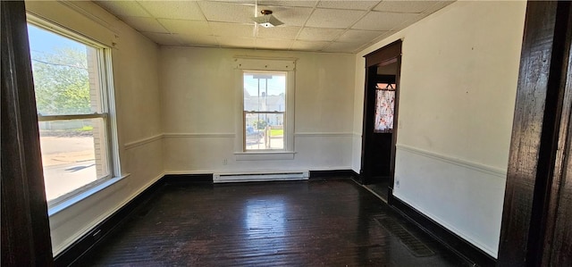 spare room featuring a drop ceiling, dark hardwood / wood-style floors, and a baseboard heating unit