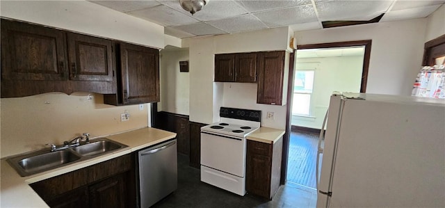 kitchen with a paneled ceiling, dark brown cabinets, white appliances, and sink