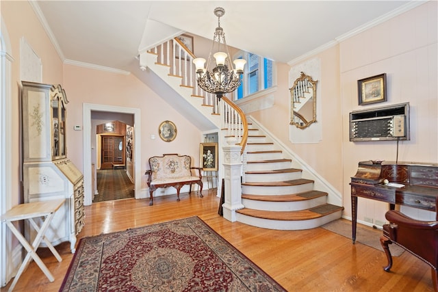 staircase with wood-type flooring, crown molding, a wall mounted air conditioner, and a notable chandelier