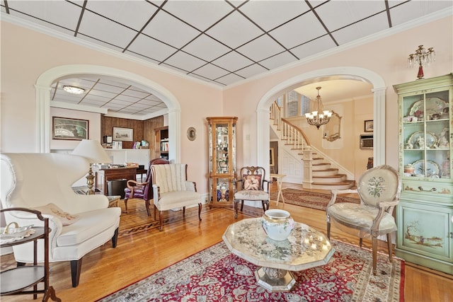 living room with an inviting chandelier, crown molding, and hardwood / wood-style floors