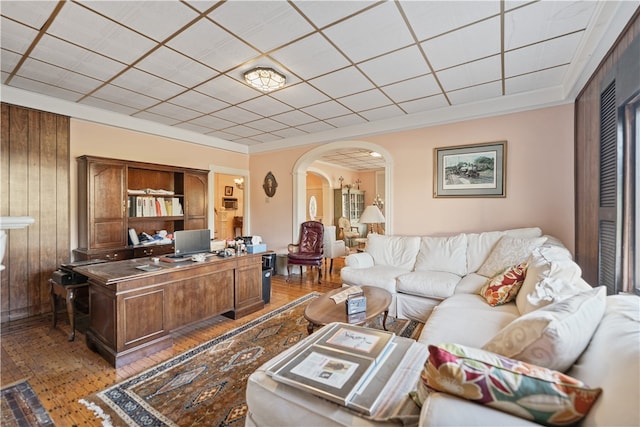 living room with ornamental molding, wood walls, and hardwood / wood-style floors