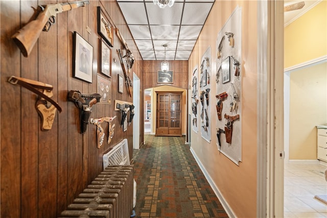 hallway featuring ornamental molding and wood walls