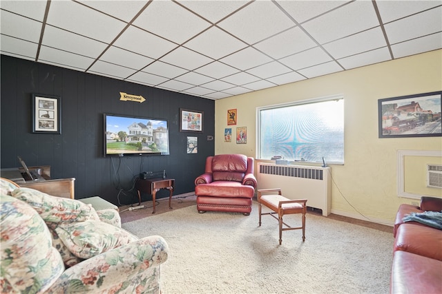 living room with carpet floors, a paneled ceiling, and radiator heating unit