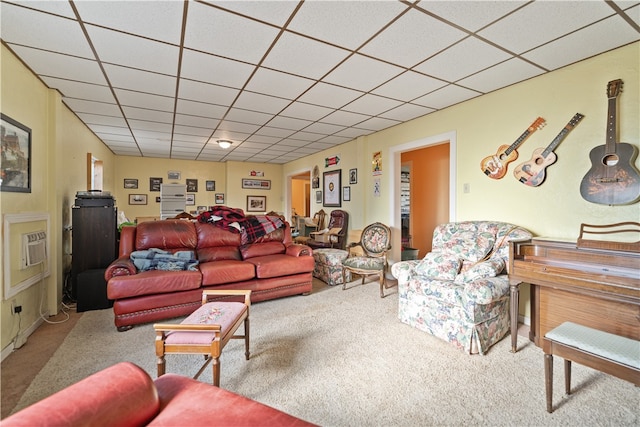 carpeted living room featuring a drop ceiling and a wall mounted air conditioner