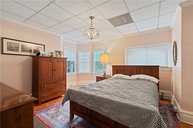 bedroom featuring a paneled ceiling, hardwood / wood-style floors, and crown molding