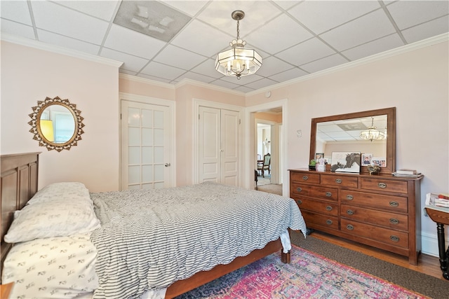 bedroom with hardwood / wood-style flooring, a drop ceiling, and ornamental molding