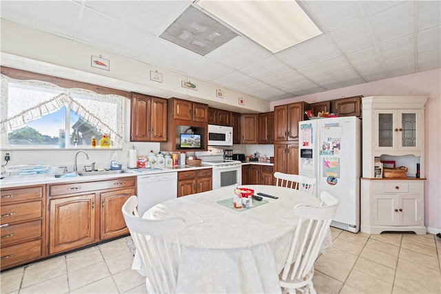 kitchen featuring white appliances, a center island, light tile patterned flooring, and sink