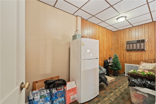 kitchen with white refrigerator, wood walls, and a paneled ceiling