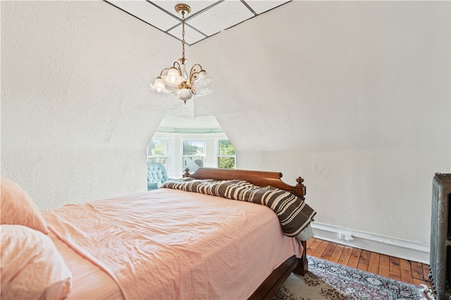 bedroom with vaulted ceiling, hardwood / wood-style flooring, and a notable chandelier