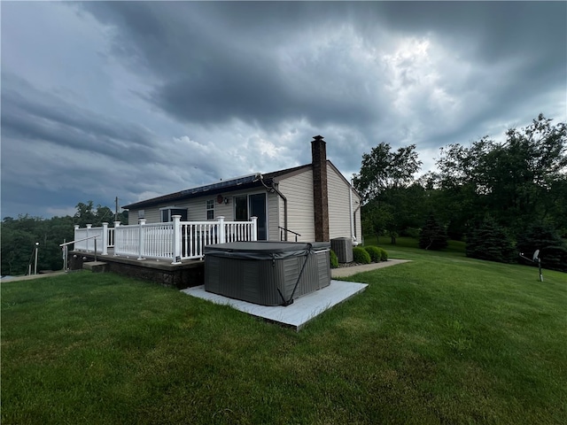 rear view of house featuring a hot tub and a yard