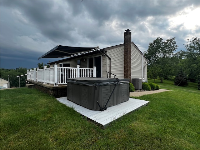 back of house featuring a hot tub, a lawn, and central AC unit