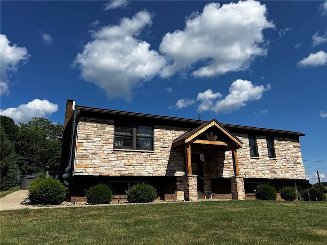 raised ranch with stone siding and a front lawn